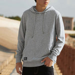 Person wearing a gray hoodie with a blurred outdoor background