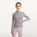 Woman wearing a gray zip-up jacket and pink leggings on a white background