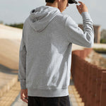 Person wearing a gray hoodie outdoors with a blurred background