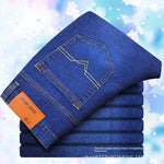 Stack of blue jeans with an orange tag on a light blue background