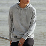 Person wearing a gray hoodie by a body of water