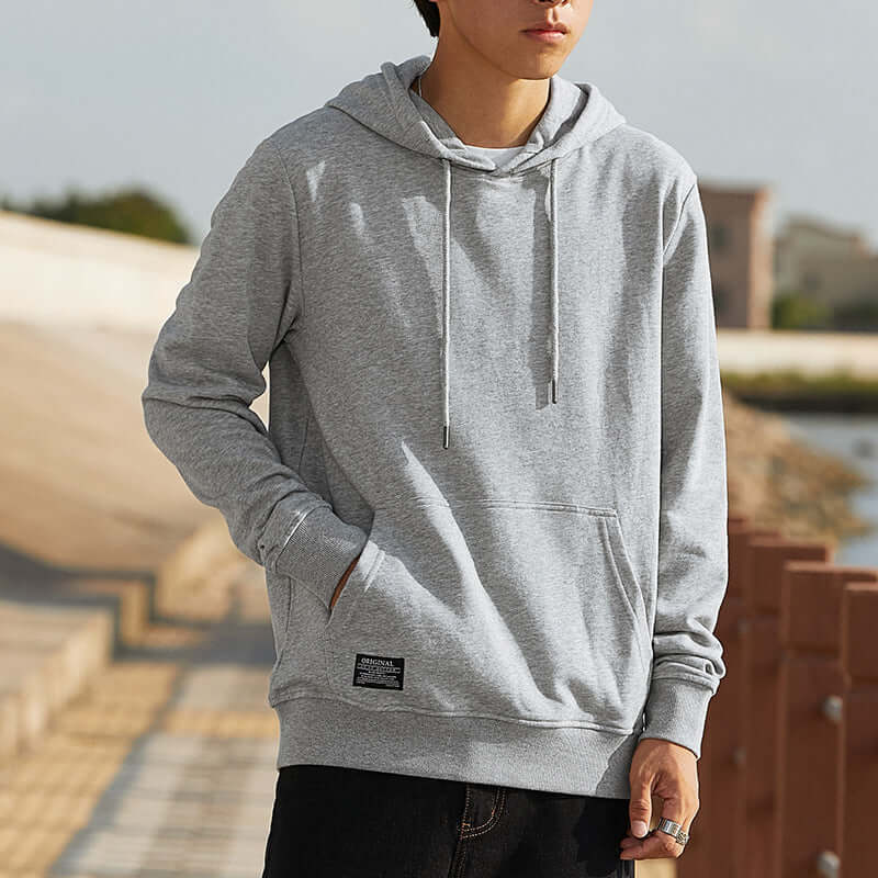 Person wearing a gray hoodie with a blurred outdoor background