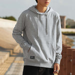 Person wearing a gray hoodie with a blurred outdoor background