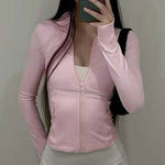Person wearing a pink zip-up jacket taking a mirror selfie.