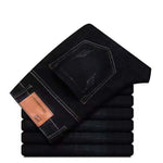 Stack of black jeans with a visible brand label on a white background