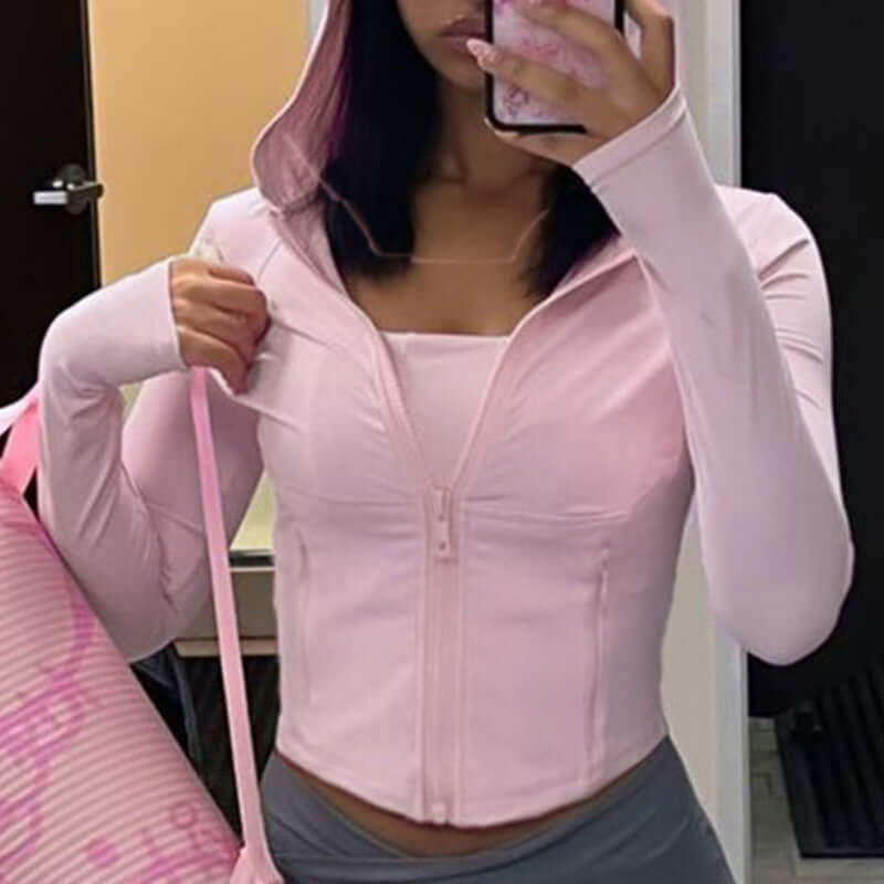 Person wearing a light pink long-sleeve top with a zipper, taking a mirror selfie.